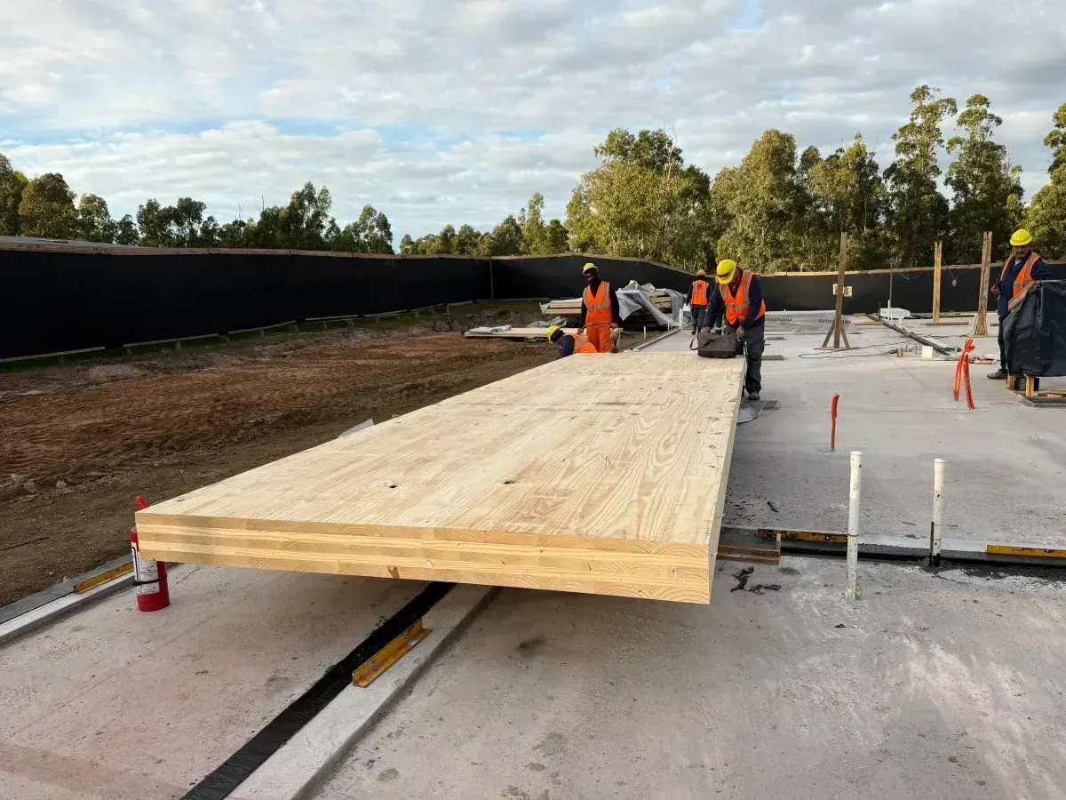 Workers positioning CLT floor panel on the slab